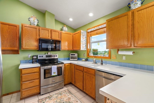 23823 E Garland Ave, Otis Orchards, WA 99027 - kitchen featuring appliances with stainless steel finishes, a sink, light countertops, light tile patterned flooring, and vaulted ceiling