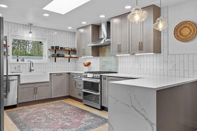4318 S Magnolia St, Spokane, WA 99203 - kitchen with wall chimney exhaust hood, stainless steel appliances, a sink, a skylight, and light stone countertops