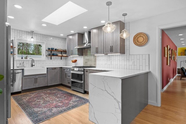 4318 S Magnolia St, Spokane, WA 99203 - kitchen with wall chimney range hood, stainless steel appliances, gray cabinets, a sink, and a skylight