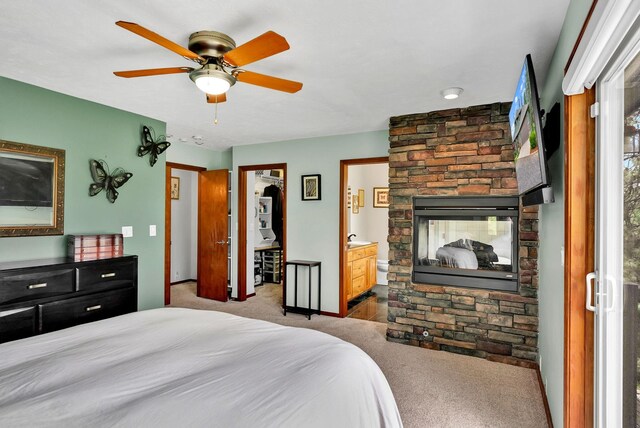 6533 D Lois Way, Nine Mile Falls, WA 99026 - carpeted bedroom with a stone fireplace, ensuite bath, a ceiling fan, and baseboards
