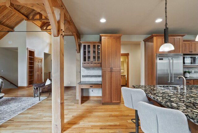 1122 E Hangman Ln, Spokane, WA 99224 - kitchen featuring appliances with stainless steel finishes, light wood-style floors, a sink, decorative backsplash, and glass insert cabinets