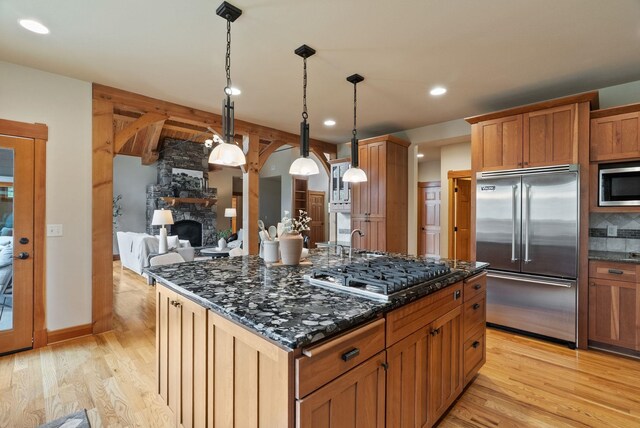 1122 E Hangman Ln, Spokane, WA 99224 - kitchen featuring built in appliances, light wood-style flooring, a stone fireplace, dark stone counters, and recessed lighting