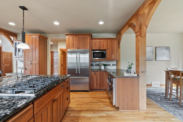 1122 E Hangman Ln, Spokane, WA 99224 - kitchen featuring built in appliances, light wood finished floors, backsplash, dark stone countertops, and recessed lighting