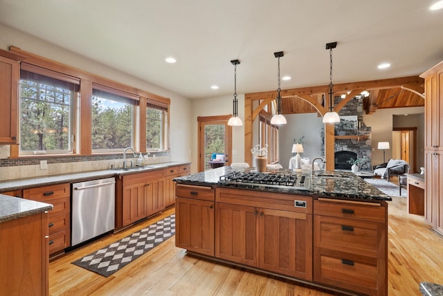 1122 E Hangman Ln, Spokane, WA 99224 - kitchen featuring stainless steel appliances, a sink, dark stone counters, a center island, and light wood-style flooring