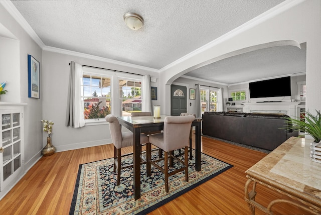 3507 E 28th Ave, Spokane, WA 99223 - dining area with arched walkways, a textured ceiling, wood finished floors, a fireplace, and crown molding
