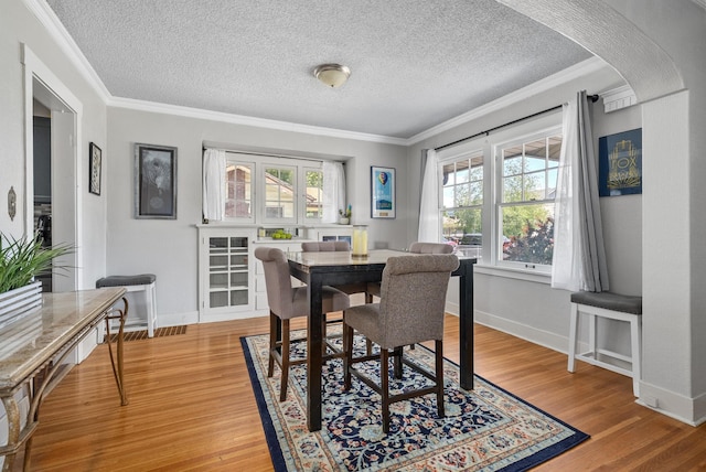 3507 E 28th Ave, Spokane, WA 99223 - dining room with ornamental molding, a textured ceiling, light wood-type flooring, and baseboards