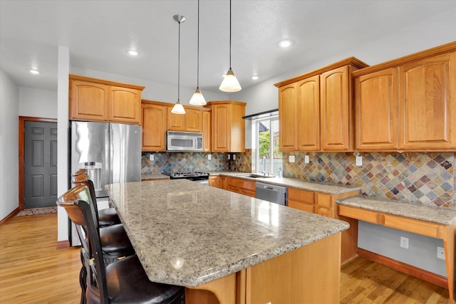 903 E Harding Ct, Spokane, WA 99218 - kitchen featuring stainless steel appliances, a sink, light wood-type flooring, a kitchen breakfast bar, and light stone counters