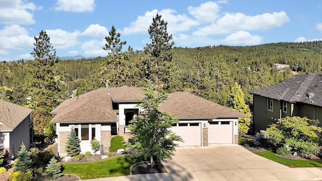 4523 S Henrys Fork Ln, Spokane, WA 99206 - view of front of property featuring a wooded view, concrete driveway, a garage, and roof with shingles