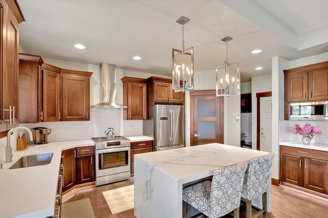 4523 S Henrys Fork Ln, Spokane, WA 99206 - kitchen featuring appliances with stainless steel finishes, wall chimney exhaust hood, a chandelier, backsplash, and light wood-style floors