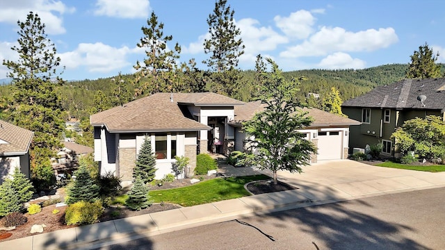 4523 S Henrys Fork Ln, Spokane, WA 99206 - prairie-style home featuring concrete driveway, an attached garage, a wooded view, stucco siding, and roof with shingles