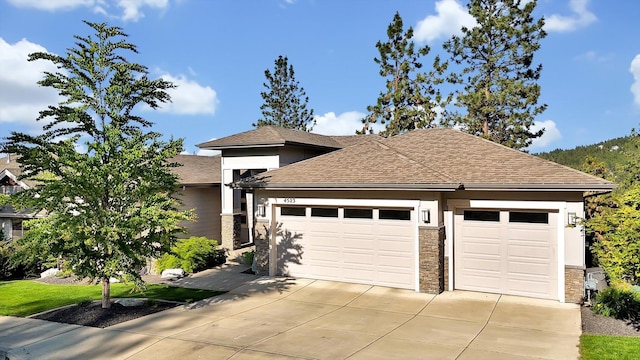 4523 S Henrys Fork Ln, Spokane, WA 99206 - view of front facade with an attached garage, concrete driveway, roof with shingles, and stone siding