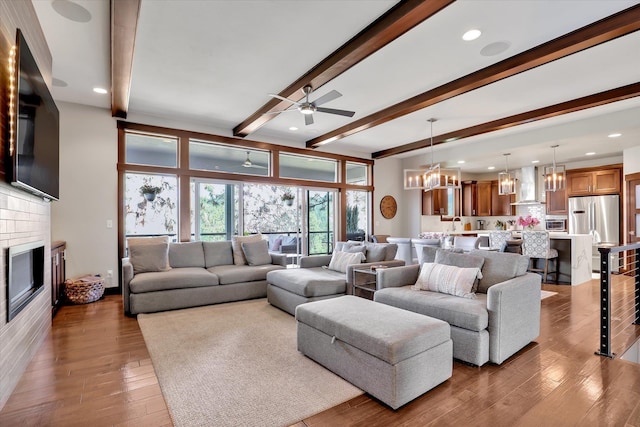 4523 S Henrys Fork Ln, Spokane, WA 99206 - living room with beamed ceiling, a chandelier, ceiling fan, a glass covered fireplace, and wood finished floors
