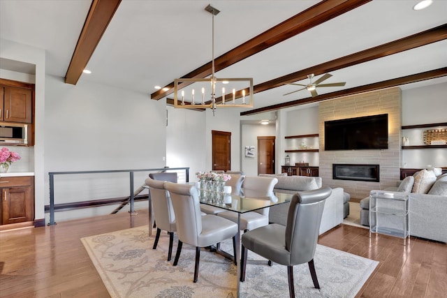 4523 S Henrys Fork Ln, Spokane, WA 99206 - dining room featuring beam ceiling, ceiling fan, a large fireplace, wood finished floors, and a chandelier