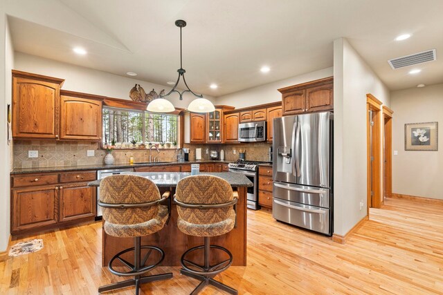 1220 E Fireside Ln, Spokane, WA 99208 - kitchen with stainless steel appliances, a kitchen island, light wood-style floors, brown cabinetry, and recessed lighting