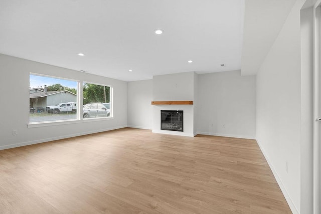 101 S W St, Chewelah, WA 99109 - unfurnished living room featuring light wood-type flooring, a glass covered fireplace, recessed lighting, and baseboards