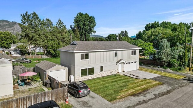 101 S W St, Chewelah, WA 99109 - view of front of property with a garage, asphalt driveway, an outbuilding, stone siding, and a shingled roof