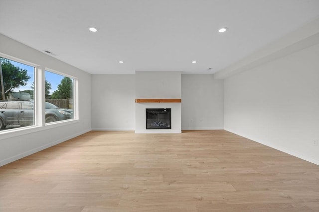101 S W St, Chewelah, WA 99109 - unfurnished living room featuring recessed lighting, a glass covered fireplace, light wood-style floors, and baseboards