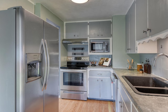 2729 W Broad Ave, Spokane, WA 99205 - kitchen with stainless steel appliances, a sink, extractor fan, light wood-style floors, and light countertops