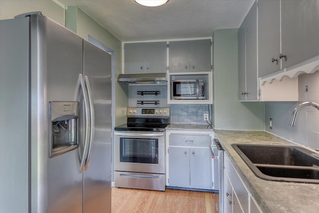 2729 W Broad Ave, Spokane, WA 99205 - kitchen with stainless steel appliances, a sink, extractor fan, light countertops, and light wood-style floors