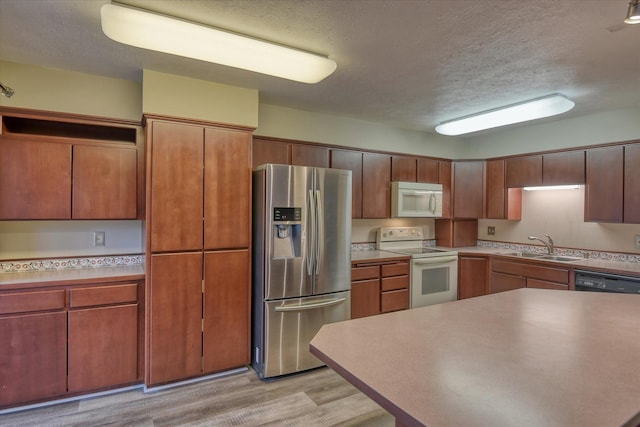 707 W 6th Ave # 33, Spokane, WA 99204 - kitchen with white appliances, a textured ceiling, light wood-style flooring, a sink, and light countertops