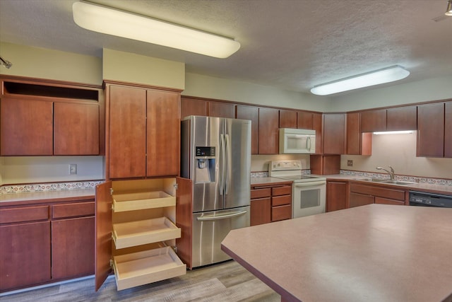 707 W 6th Ave # 33, Spokane, WA 99204 - kitchen with white appliances, a textured ceiling, a sink, light wood finished floors, and light countertops