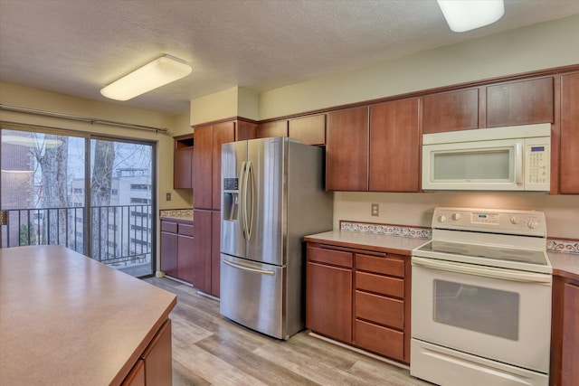 707 W 6th Ave # 33, Spokane, WA 99204 - kitchen featuring white appliances, light wood-style floors, a textured ceiling, light countertops, and brown cabinetry