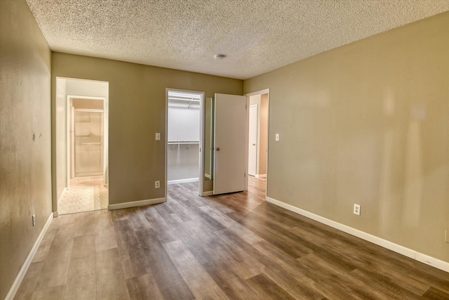 707 W 6th Ave # 33, Spokane, WA 99204 - unfurnished bedroom featuring wood finished floors, a spacious closet, baseboards, a closet, and a textured ceiling