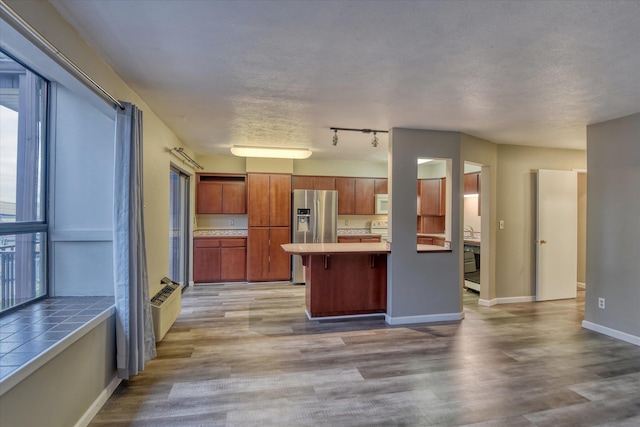 707 W 6th Ave # 33, Spokane, WA 99204 - kitchen with stainless steel fridge, wood finished floors, white microwave, a breakfast bar, and baseboards