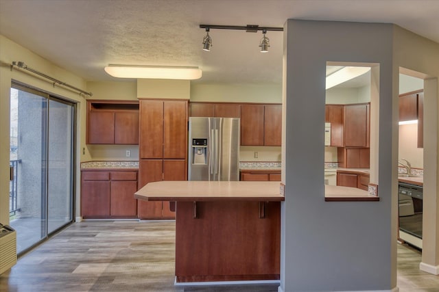 707 W 6th Ave # 33, Spokane, WA 99204 - kitchen featuring stainless steel fridge, a peninsula, dishwasher, light countertops, and a kitchen breakfast bar