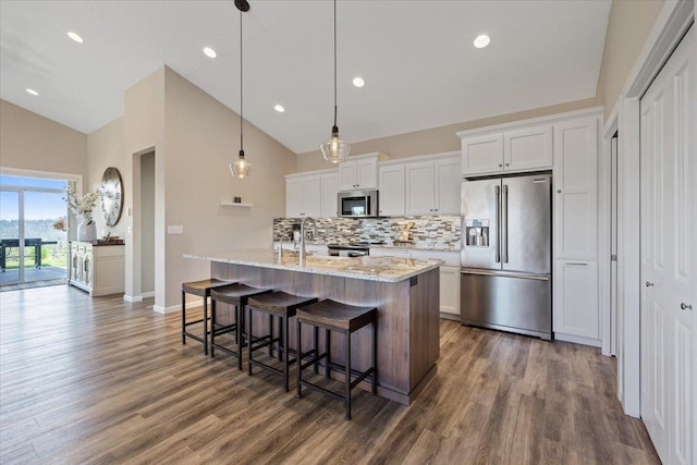 696 W Basalt Ridge Dr, Spokane, WA 99224 - kitchen featuring stainless steel appliances, tasteful backsplash, an island with sink, a breakfast bar, and dark wood-style flooring