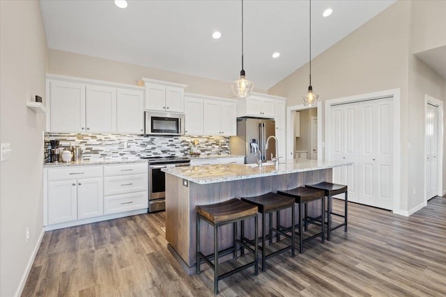 696 W Basalt Ridge Dr, Spokane, WA 99224 - kitchen featuring appliances with stainless steel finishes, tasteful backsplash, white cabinetry, dark wood-style flooring, and lofted ceiling