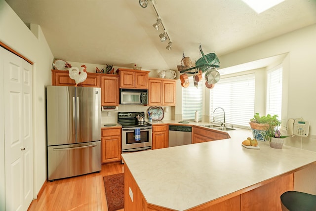 6706 S Moran View St, Spokane, WA 99224 - kitchen featuring stainless steel appliances, a sink, a peninsula, lofted ceiling, and light wood-type flooring