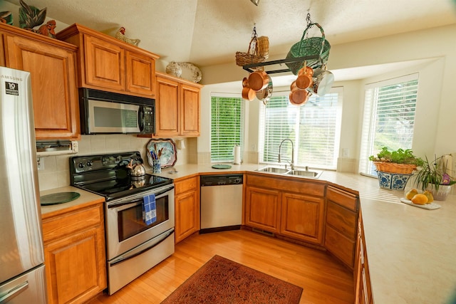 6706 S Moran View St, Spokane, WA 99224 - kitchen with stainless steel appliances, a sink, light wood-type flooring, light countertops, and tasteful backsplash