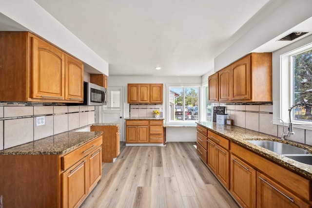 2603 E Wellesley Ave, Spokane, WA 99217 - kitchen with dark stone countertops, a sink, decorative backsplash, brown cabinetry, and stainless steel microwave