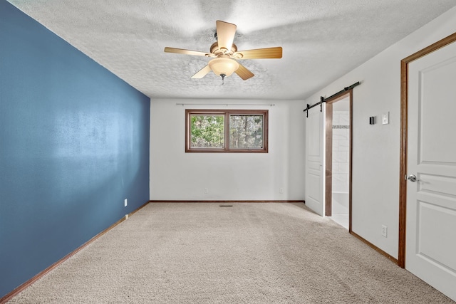 12411 E Gibbs Rd, Mica, WA 99023 - unfurnished bedroom featuring a barn door, a textured ceiling, carpet, baseboards, and ceiling fan
