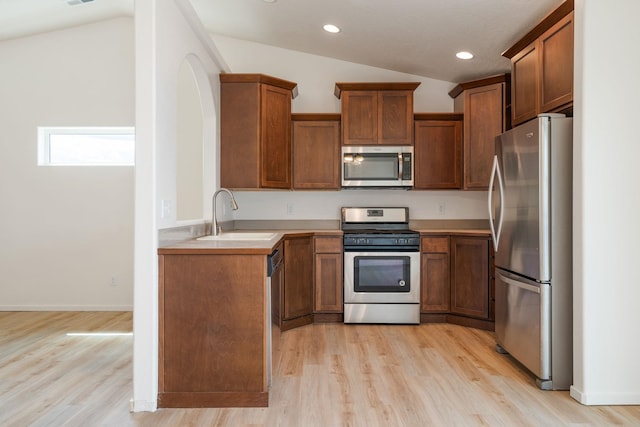 10214 W January Ct, Cheney, WA 99004 - kitchen featuring stainless steel appliances, vaulted ceiling, a sink, brown cabinetry, and light wood finished floors