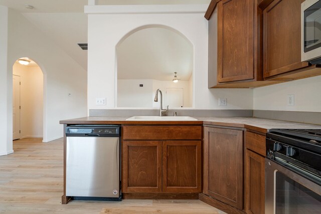 10214 W January Ct, Cheney, WA 99004 - kitchen with appliances with stainless steel finishes, a sink, arched walkways, and light wood-style floors