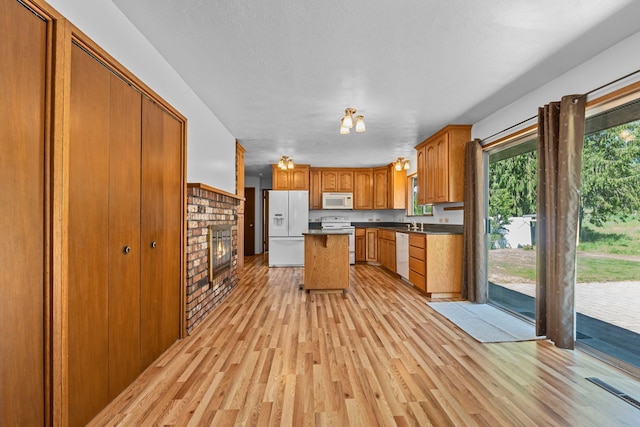 252 Davaz-Carlton Rd, Newport, WA 99156 - kitchen featuring white appliances, light wood finished floors, brown cabinets, and a brick fireplace