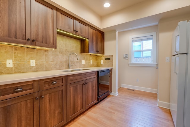 523 S Hatch St, Spokane, WA 99202 - kitchen with black dishwasher, a sink, freestanding refrigerator, brown cabinetry, and backsplash