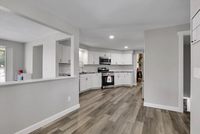 8428 N Susan Ct, Spokane, WA 99208 - kitchen featuring stainless steel appliances, backsplash, white cabinets, wood finished floors, and baseboards