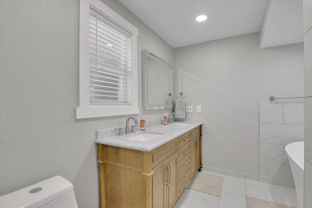 8428 N Susan Ct, Spokane, WA 99208 - bathroom featuring marble finish flooring, a freestanding bath, double vanity, toilet, and baseboards