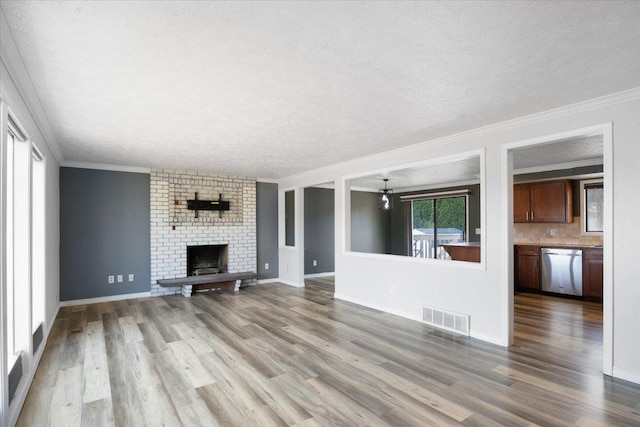 6106 W Kittitas Ct, Spokane, WA 99208 - unfurnished living room with a textured ceiling, wood finished floors, crown molding, a fireplace, and baseboards