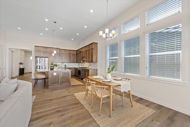 4756 W Lex Ave, Spokane, WA 99208 - dining space featuring a chandelier, a towering ceiling, recessed lighting, light wood-style flooring, and baseboards