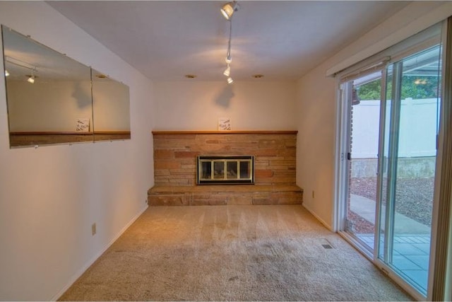 5516 N Fleming St, Spokane, WA 99205 - unfurnished living room featuring rail lighting, carpet floors, a stone fireplace, and baseboards