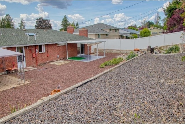 5516 N Fleming St, Spokane, WA 99205 - rear view of house with brick siding, a patio area, a fenced backyard, a shingled roof, and a chimney