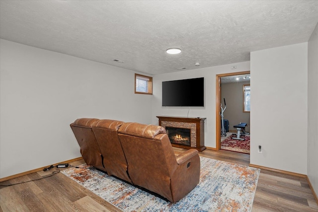 1216 W Candlewood Ct, Spokane, WA 99218 - living area with light wood-style flooring, baseboards, a lit fireplace, healthy amount of natural light, and a textured ceiling