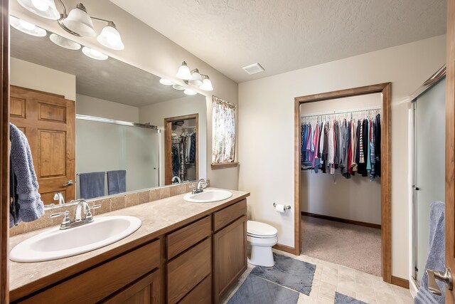 1811 S Canyon Woods Ln, Spokane, WA 99224 - full bath featuring a walk in closet, double vanity, a stall shower, baseboards, and toilet