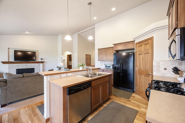 1811 S Canyon Woods Ln, Spokane, WA 99224 - kitchen featuring black appliances, a sink, light wood finished floors, arched walkways, and decorative backsplash