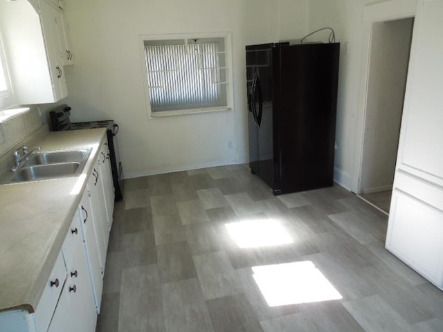 917 E Walton Ave, Spokane, WA 99207 - kitchen featuring black fridge with ice dispenser, range, white cabinets, and light countertops