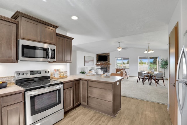 1002 N Oasis Ave, Deer Park, WA 99006 - kitchen featuring stainless steel appliances, open floor plan, light countertops, a large fireplace, and a peninsula